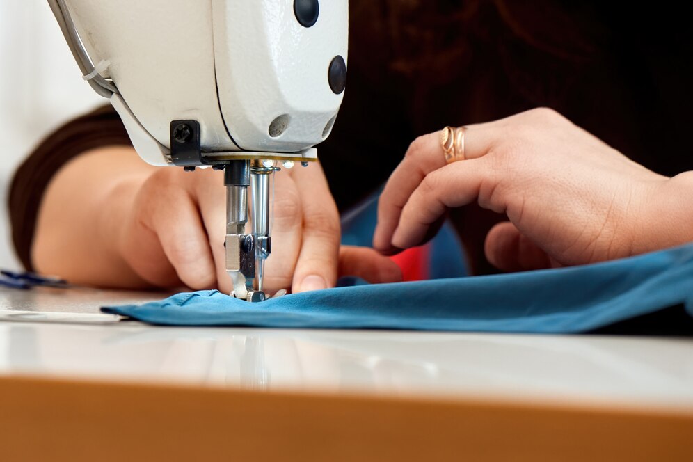 woman-working-sewing-machine-with-blue-fabric_1268-14719